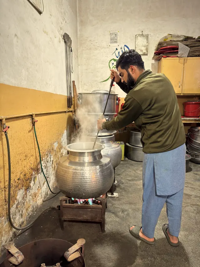 A cook stirring a steaming deg in our kitchen